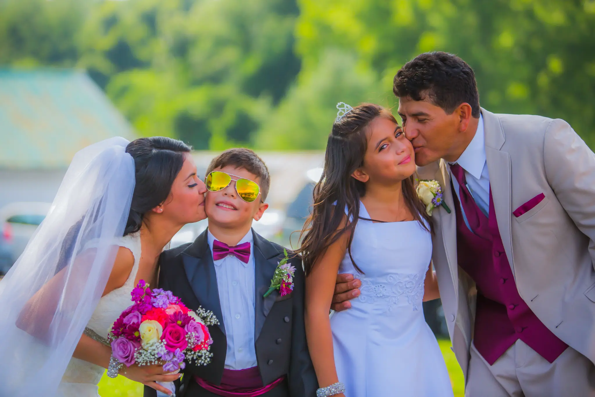 Bride and groom kissing their children on the cheek